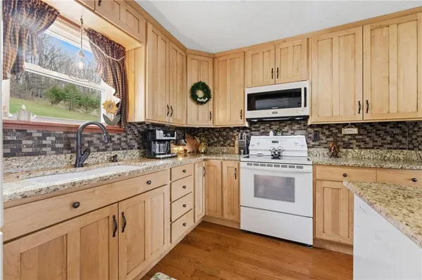 a kitchen with granite countertop white cabinets sink and stainless steel appliances