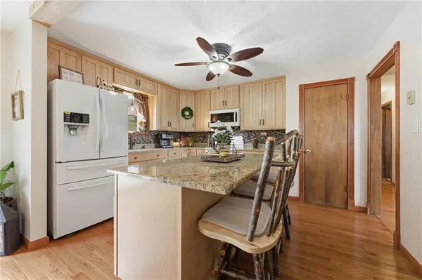 a kitchen with stainless steel appliances granite countertop a dining table chairs refrigerator and cabinets