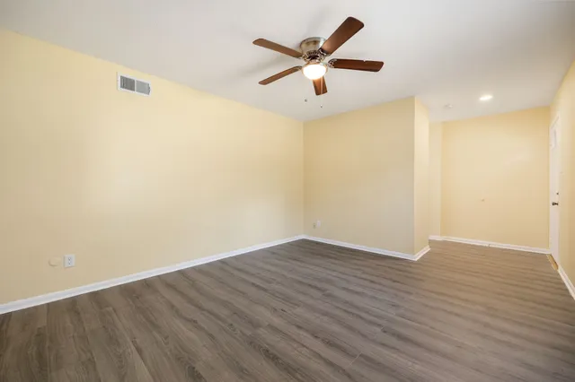 an empty room with wooden floor and ceiling fan