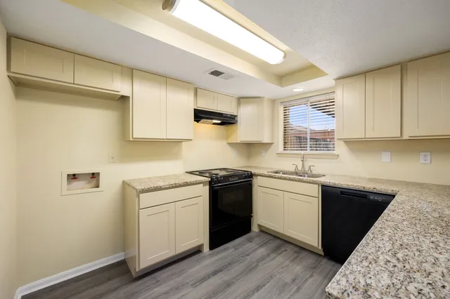 a kitchen with a sink dishwasher cabinets and wooden floor