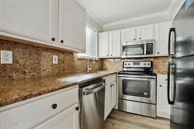 a kitchen with white cabinets stainless steel appliances and sink