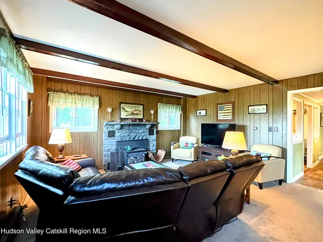 a living room with furniture a flat screen tv and floor to ceiling windows