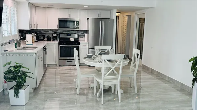 a kitchen with stainless steel appliances kitchen island granite countertop a refrigerator a stove a sink dishwasher and a dining table with wooden floor