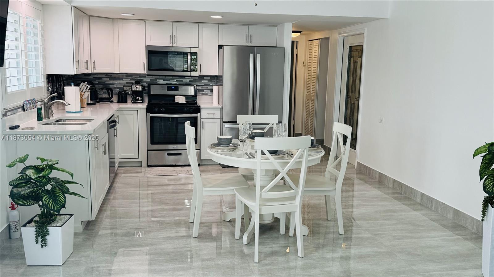 443 4th Road Key Largo, FL 33037 - Photo 3 of 17 a kitchen with stainless steel appliances kitchen island granite countertop a refrigerator a stove a sink dishwasher and a dining table with wooden floor