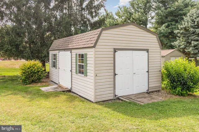 a view of a white house with a small yard and large tree
