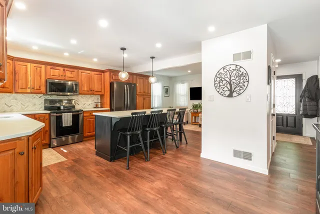 a open kitchen with stainless steel appliances granite countertop a stove top oven a sink a dining table and chairs with wooden floor