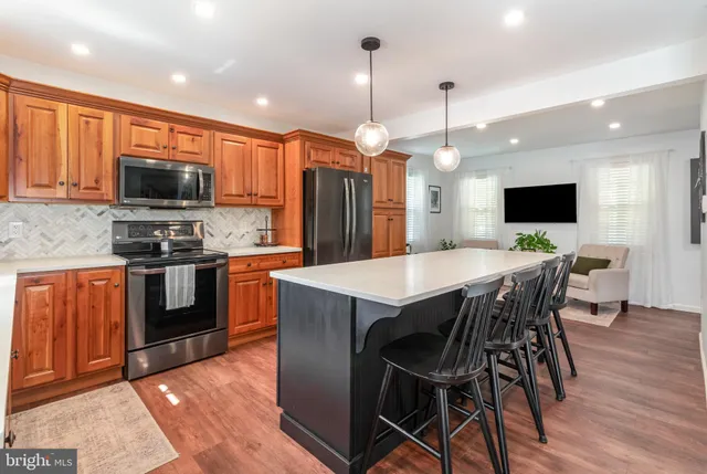 a kitchen with stainless steel appliances a stove a sink a microwave a refrigerator a stove a dining table and chairs with wooden floor