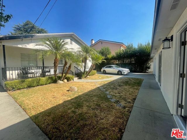 a backyard of a house with plants and palm tree