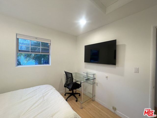 a bedroom with a bed wooden floor and a window