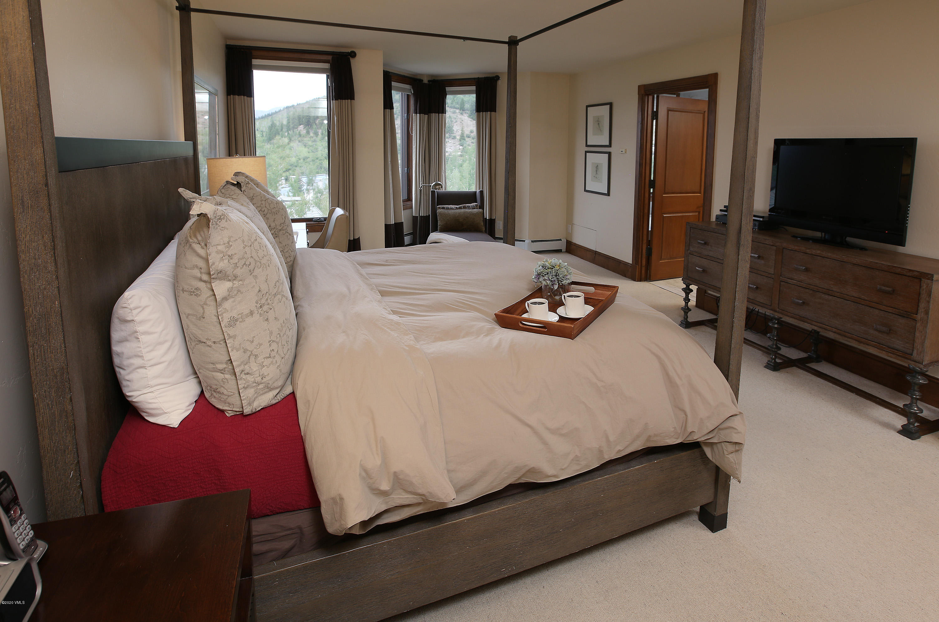 62 Highlands Lane, Unit R602 Beaver Creek, CO 81620 - Photo 22 of 30 a bed sitting in a bedroom next to a window with pc on the table and a flat screen tv