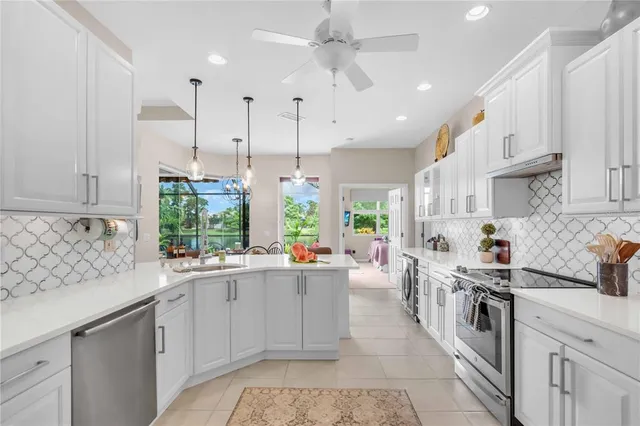 a kitchen with stainless steel appliances a sink a stove a refrigerator cabinets and a window