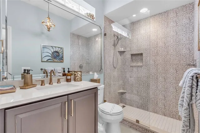 a bathroom with a granite countertop sink a toilet a shower and a mirror