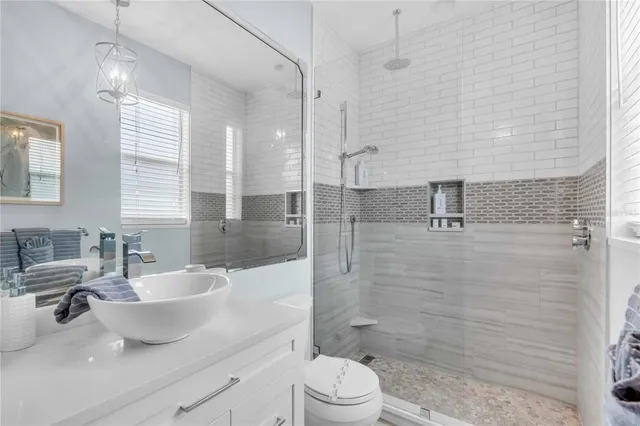 a bathroom with a sink a toilet a mirror and shower