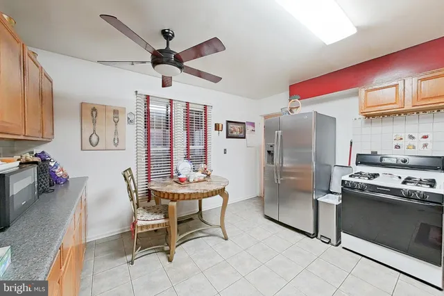 a kitchen with stainless steel appliances kitchen island granite countertop a table chairs and a refrigerator