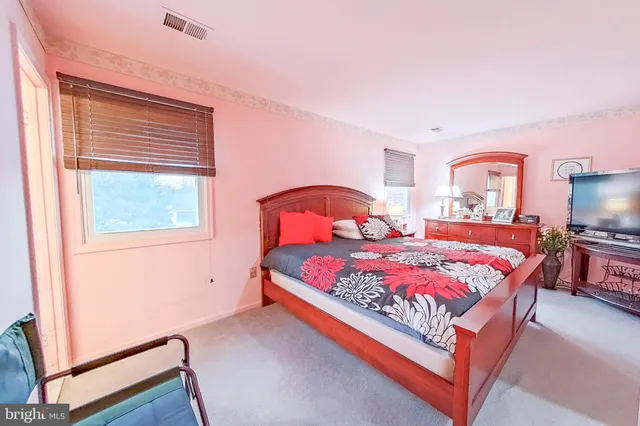 a bedroom with a bed and a flat tv screen on dresser