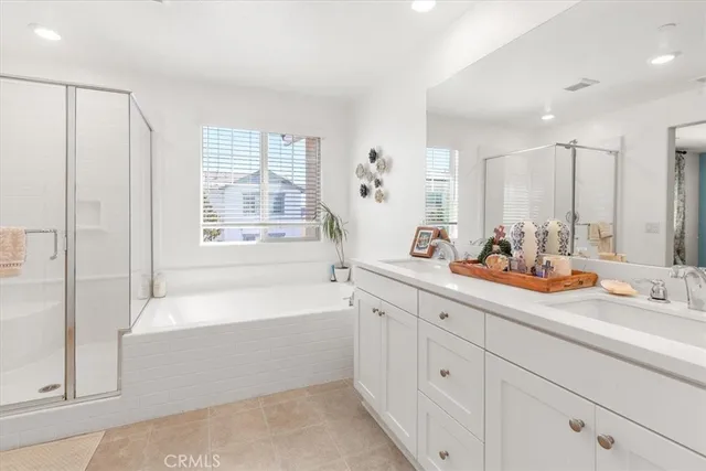 a bathroom with a double vanity sink bathtub and next to a window