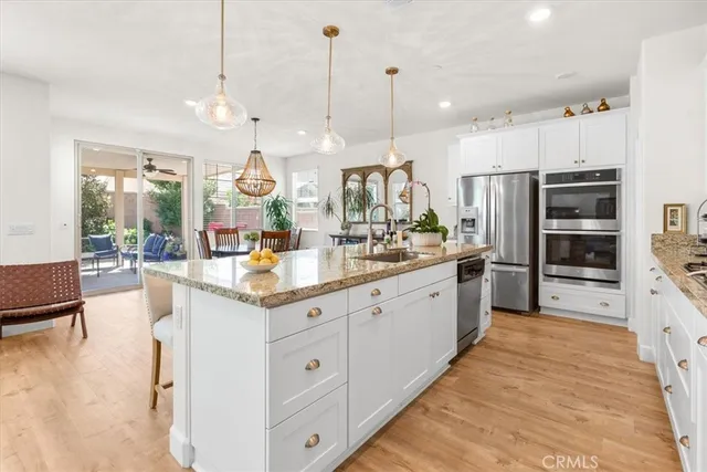 a large white kitchen with a large island in the center and stainless steel appliances
