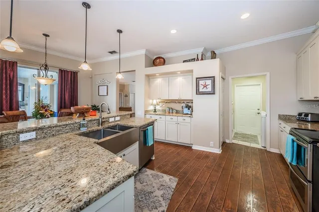 a large kitchen with kitchen island a stove a sink a refrigerator and wooden floor