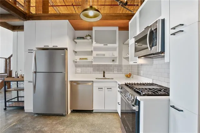 a kitchen with stainless steel appliances granite countertop a refrigerator a stove and a sink with wooden floor