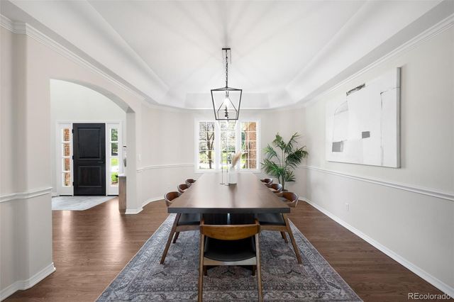 a dining room with chandelier and wooden floor