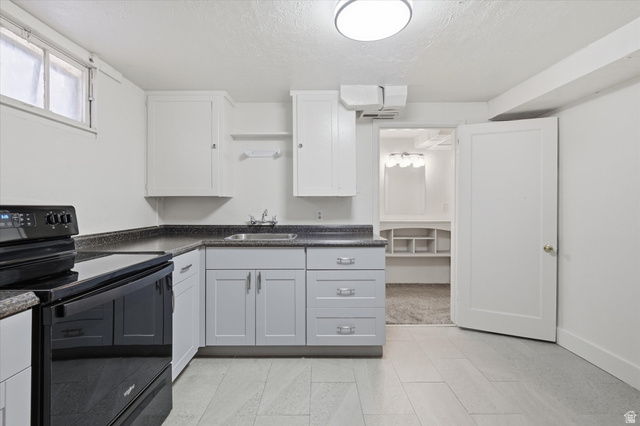 744 North 500 East Logan, UT 84321 - Photo 20 of 29 Basement Kitchen with black electric range oven, dark countertops, and a textured ceiling