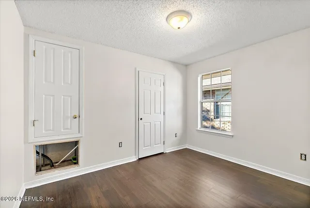 an empty room with wooden floor closet and windows