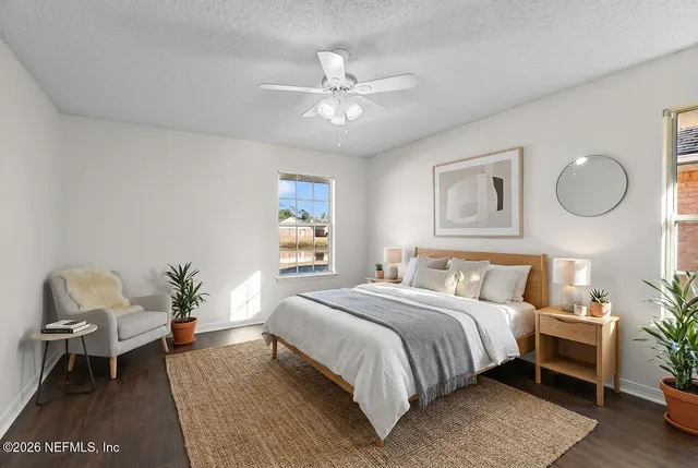 a bedroom with a bed table chair and a window