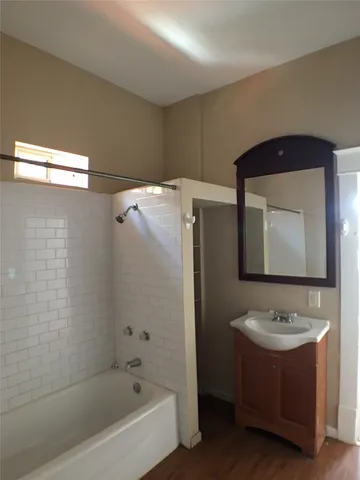 a bathroom with a bathtub shower sink and mirror