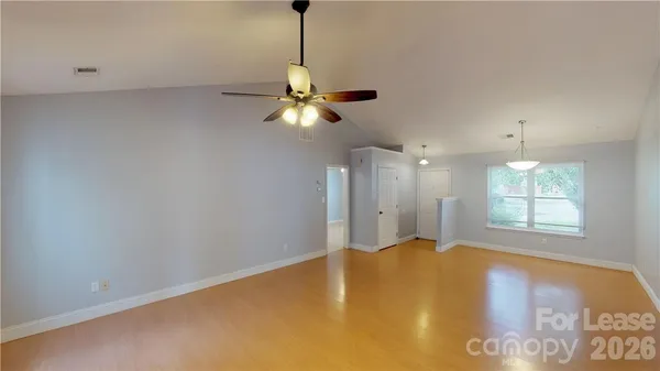 a view of an empty room and chandelier fan