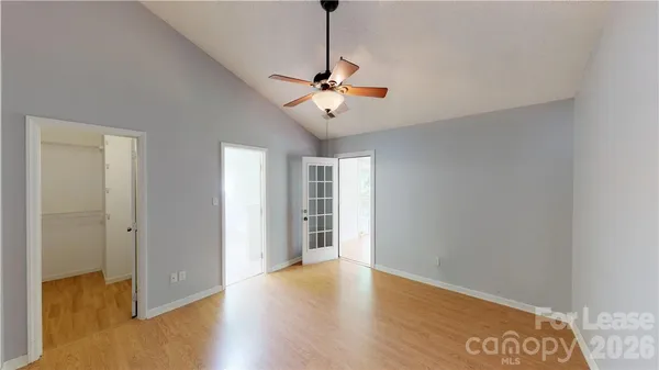 a view of an empty room with chandelier fan and wooden floor