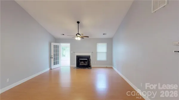 an empty room with fireplace chandelier and windows