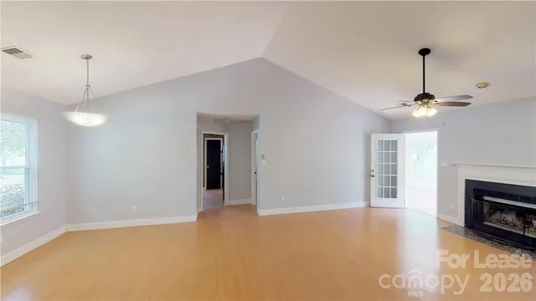 a view of an empty room with window and chandelier fan