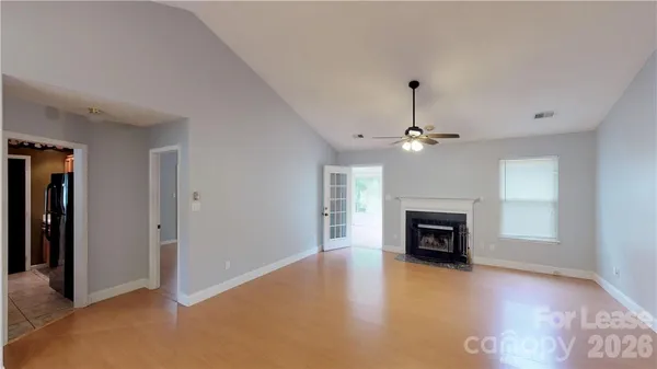 an empty room with fireplace cabinet and windows