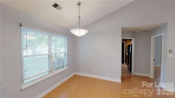 a view of an empty room with window and chandelier fan