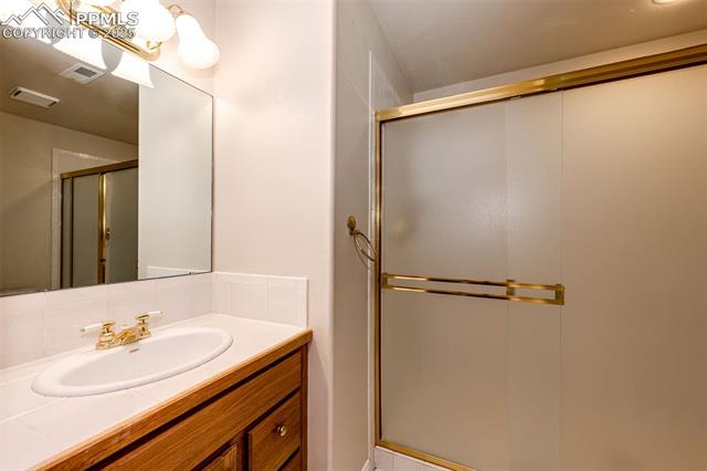 19340 Furrow Road Monument, CO 80132 - Photo 48 of 50 Bathroom featuring visible vents, a stall shower, vanity, and tasteful backsplash