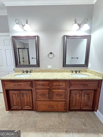 a bathroom with a granite countertop double vanity sink and a mirror