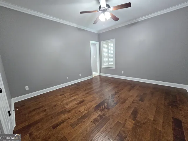 an empty room with wooden floor and fan