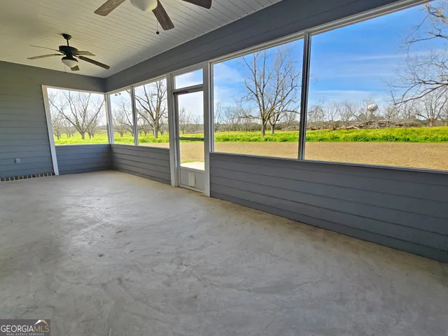 an empty room with windows and ceiling fan