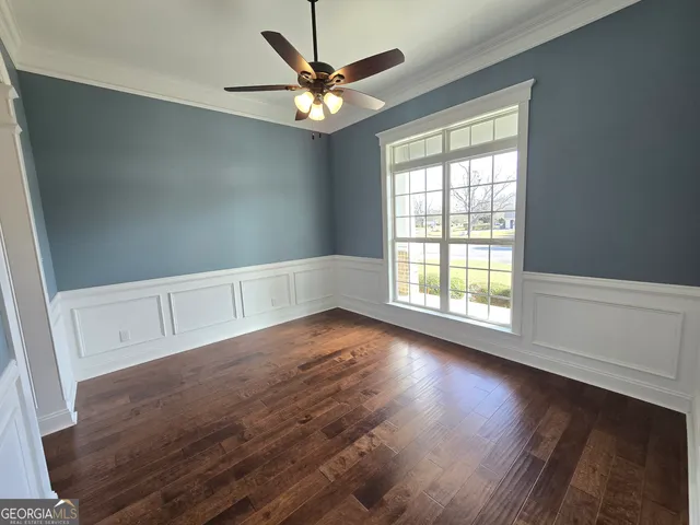 an empty room with wooden floor fan and windows