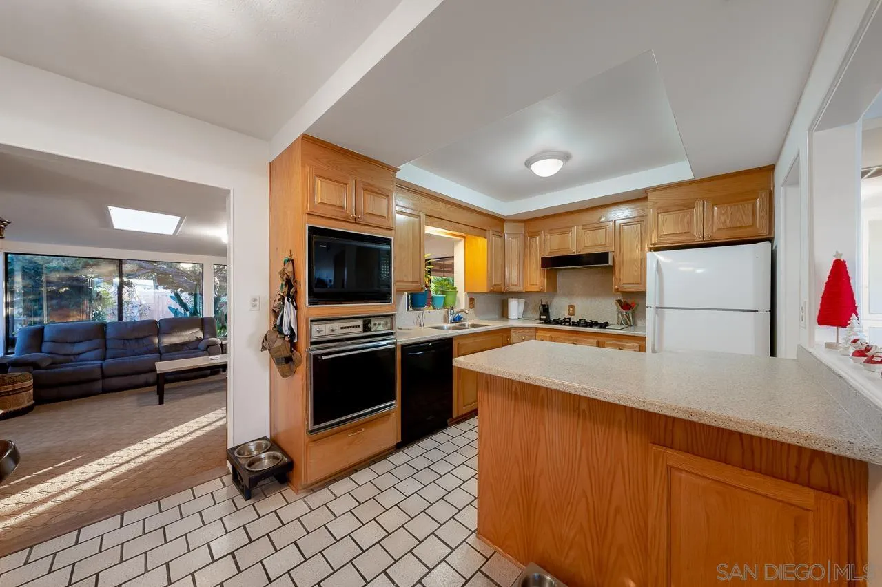 1225 Andover Road El Cajon, CA 92019 - Photo 11 of 27 a kitchen with stainless steel appliances granite countertop a refrigerator a stove and a sink with wooden floor