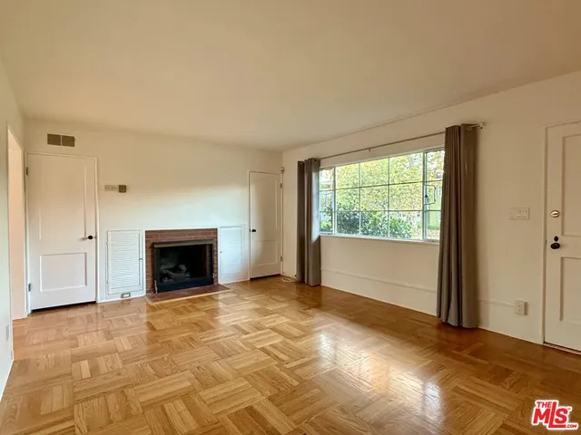 a view of an empty room with a fireplace and a window