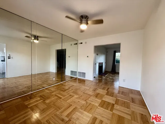 a view of an empty room with window and wooden floor