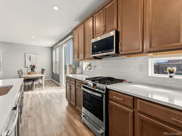 a kitchen with stainless steel appliances granite countertop a stove top oven a sink dishwasher and cabinets with wooden floor
