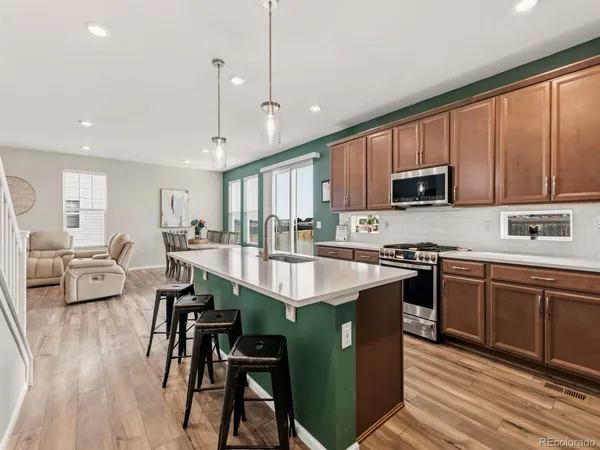 a kitchen with stainless steel appliances granite countertop wooden cabinets a dining table and chairs