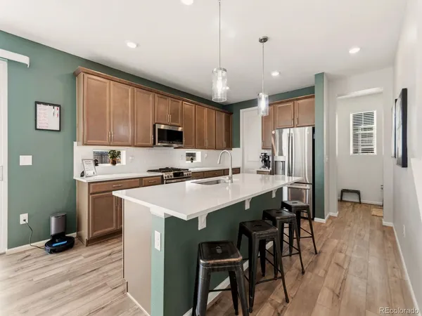 a kitchen with stainless steel appliances granite countertop a table chairs refrigerator and microwave