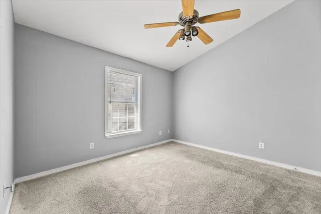 an empty room with chandelier fan and windows