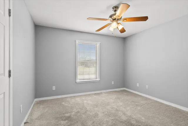 an empty room with a chandelier fan and windows