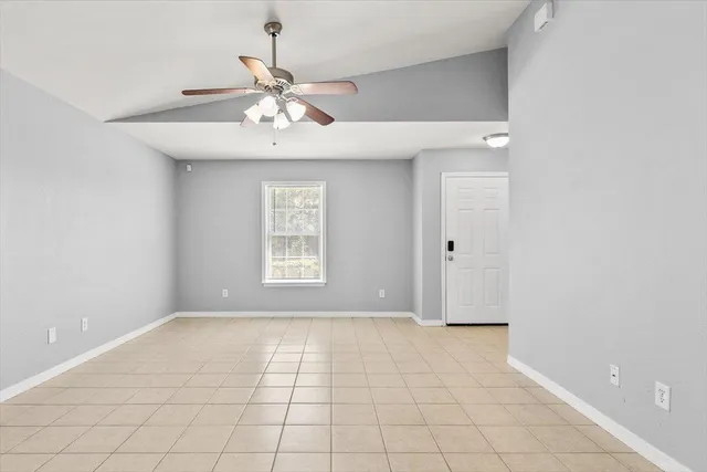 a view of an empty room with chandelier fan
