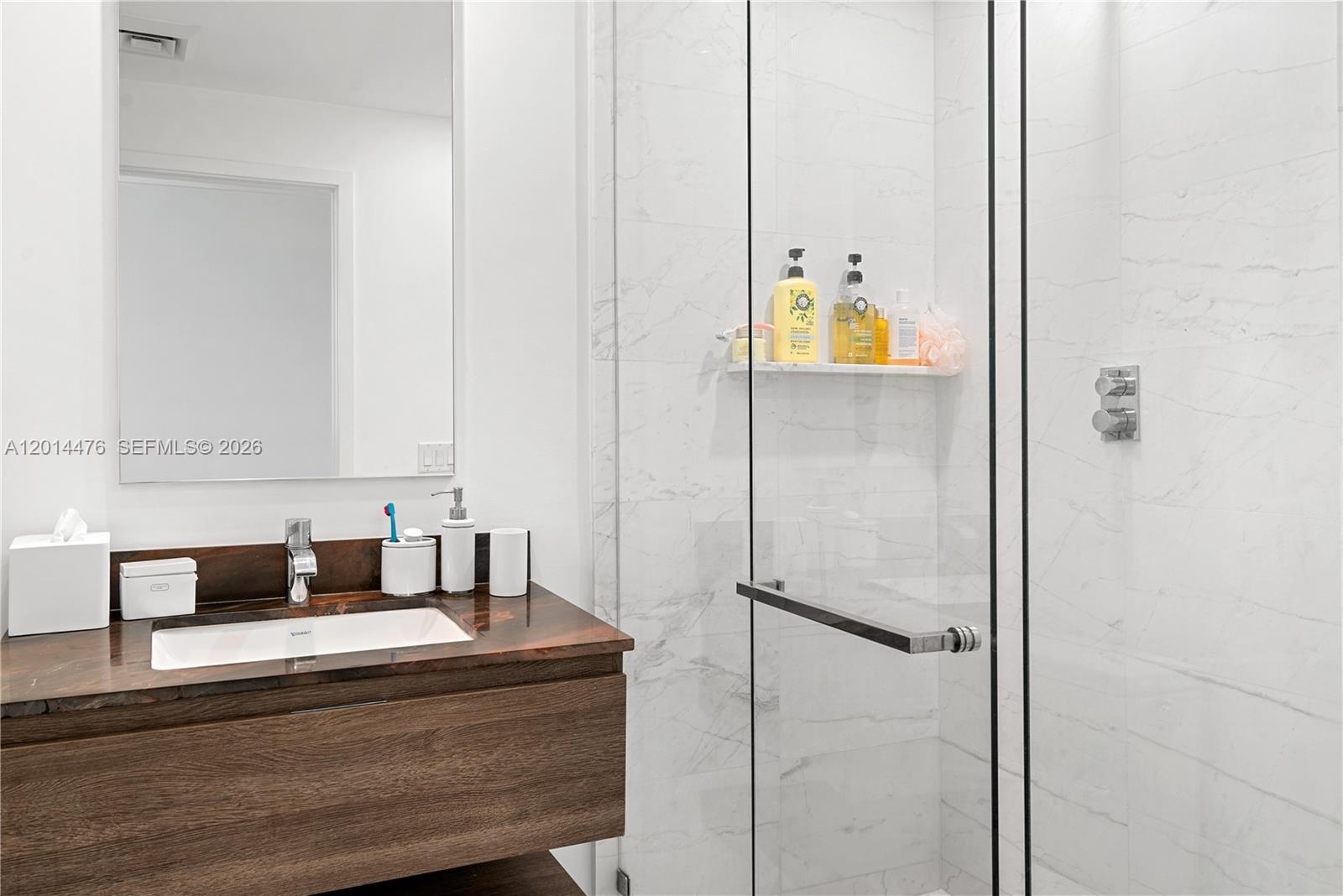 360 Ocean Drive, Unit 1106S Key Biscayne, FL 33149 - Photo 16 of 67 Bathroom – A contemporary bathroom includes a floating wood vanity, dark stone countertop, undermount sink, and a glass-enclosed marble-look shower. Clean white walls and polished finishes give the space a crisp, spa-inspired feel.