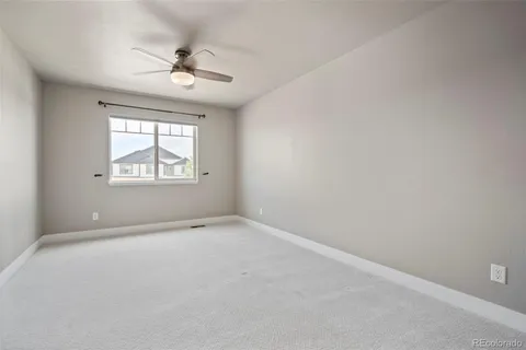 an empty room with windows and ceiling fan